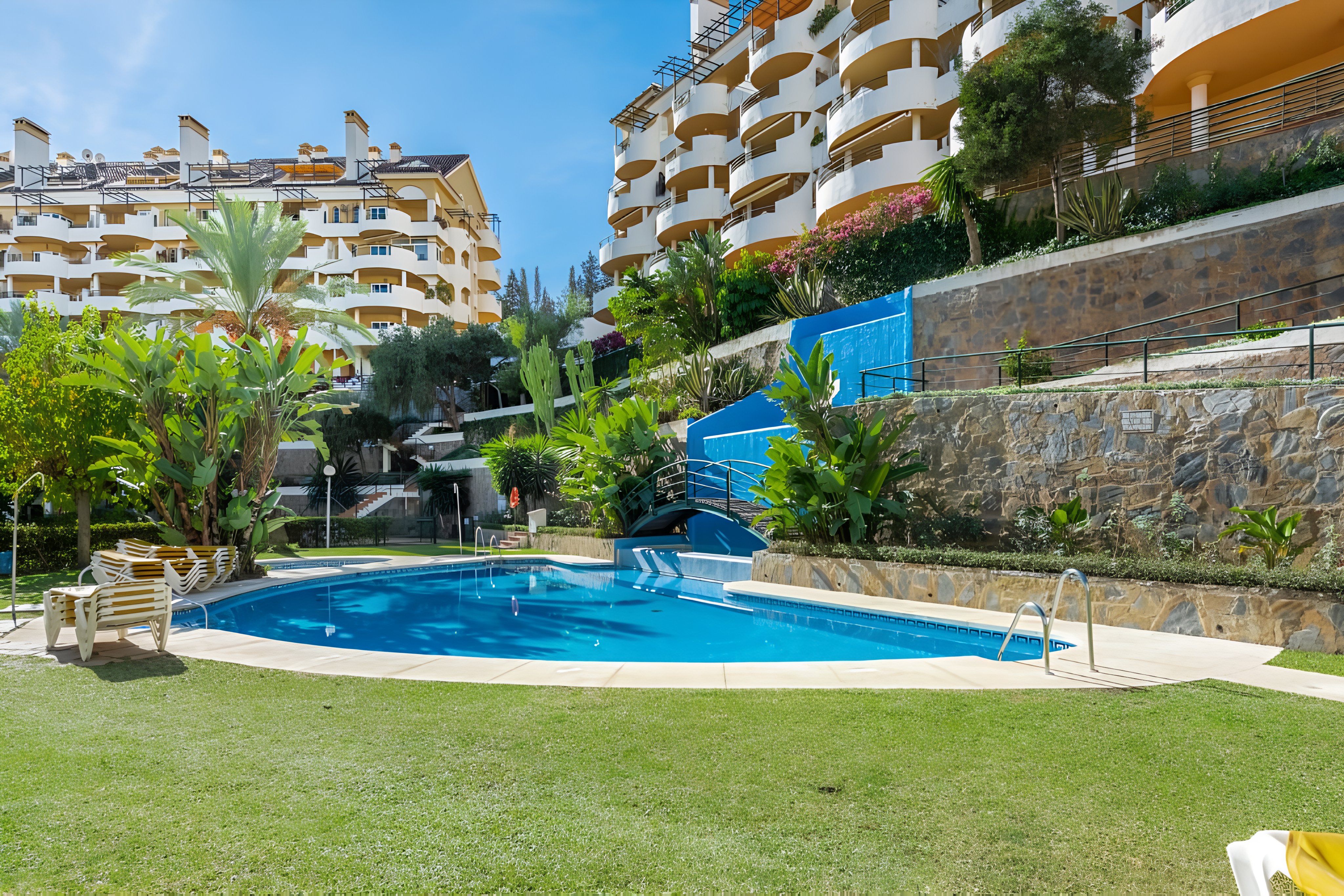 Señorío de Aloha building facade with pool and sun loungers